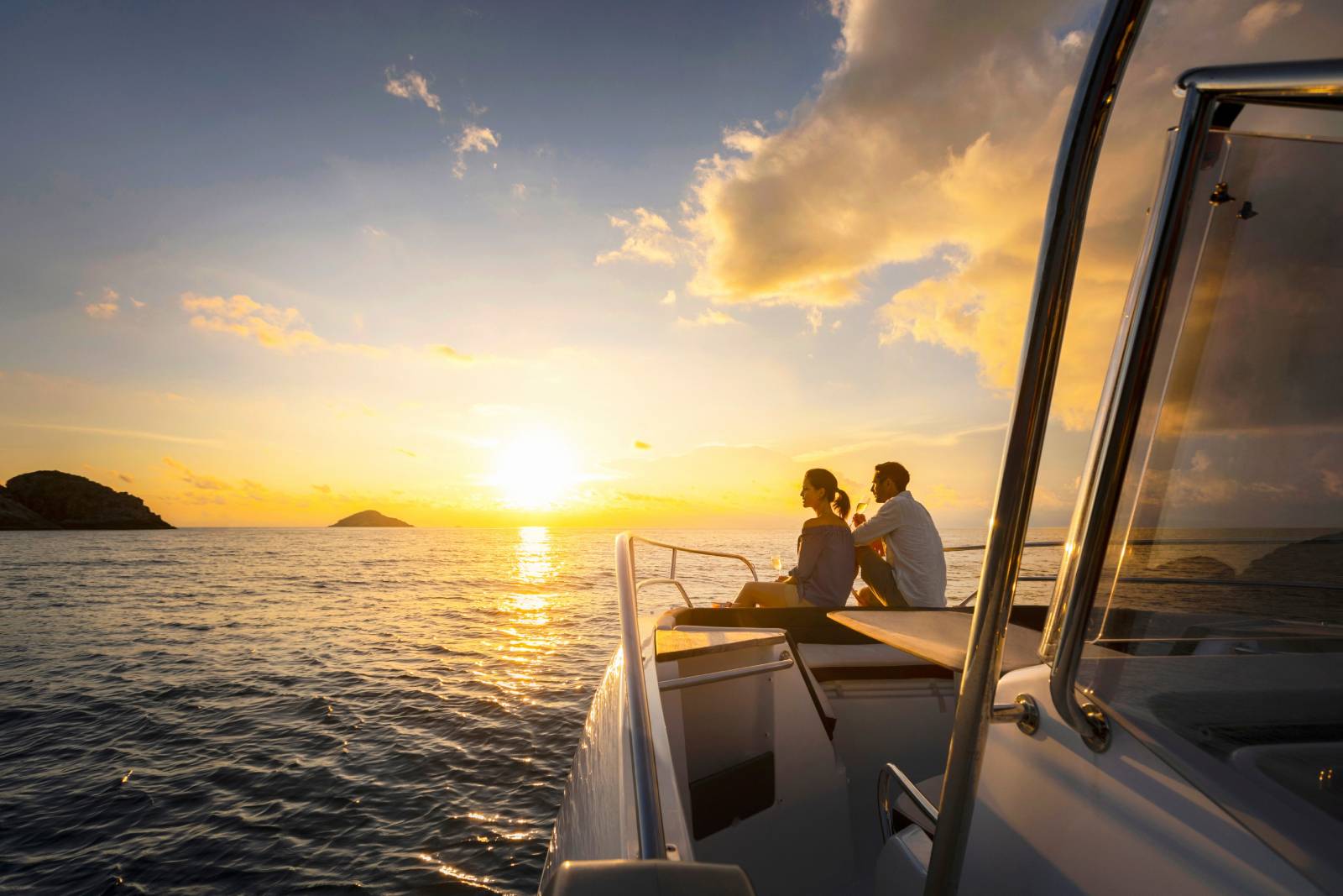 couple on honeymoon watching sun set on a speedboat