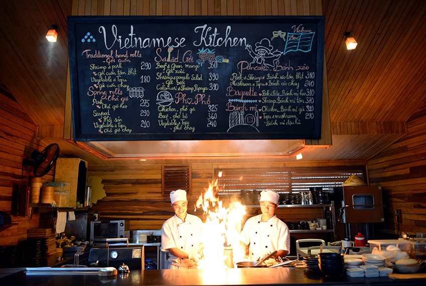 Chefs cooking in an open kitchen at by The Market Restaurant of Six Senses Con Dao