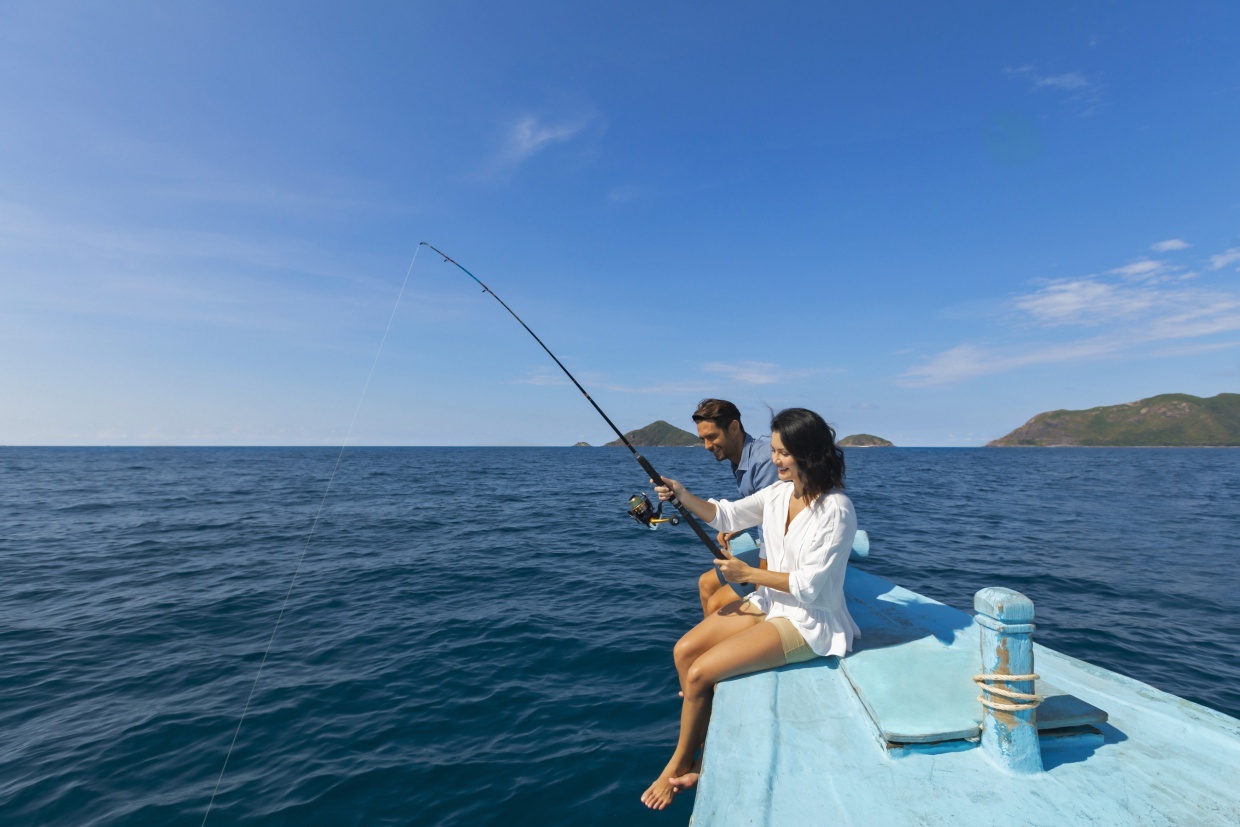 Couple fishing on a blue boat out on the ocean of Con Dao