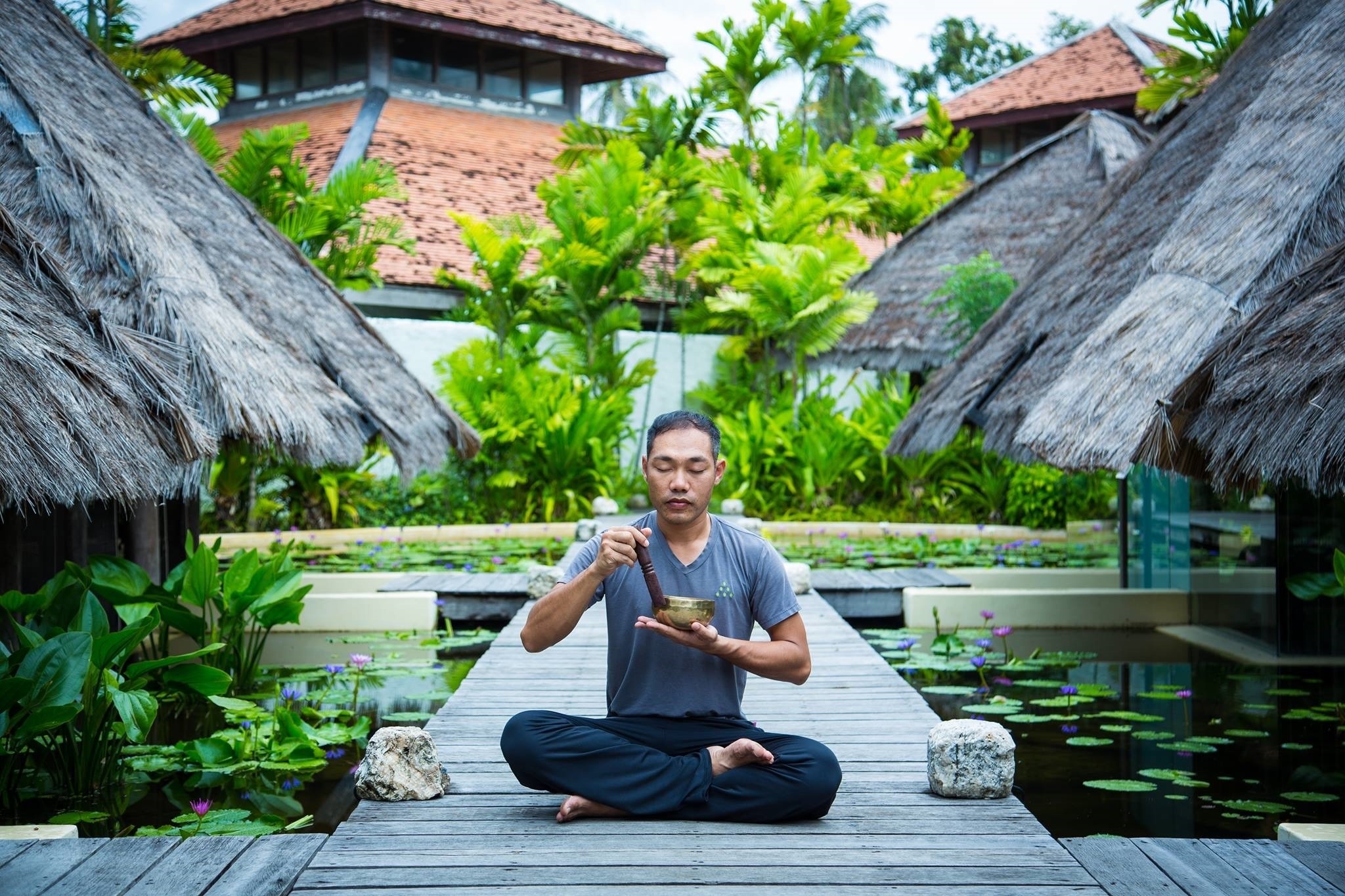 Man practicing singing bowl by the ponds in at Six Senses Con Dao